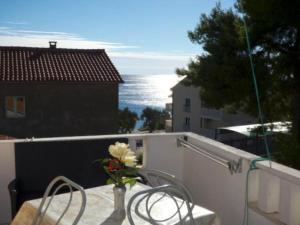 ein Tisch mit einer Vase mit Blumen auf einem Balkon in der Unterkunft Beachfront Apartments Pla a - Two Bedroom Apartment A2 in Ivan Dolac + 2 Fotos