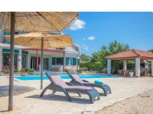 Un grupo de sillas y sombrillas junto a una piscina. en Villa P - Holiday Home, en Šibenik