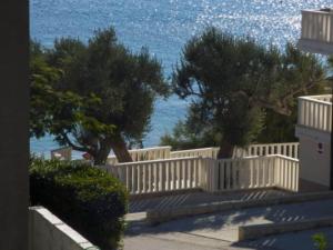 ein weißer Zaun mit zwei Bäumen vor dem Wasser in der Unterkunft Beachfront Apartments Pla a - Two Bedroom Apartment A2 in Ivan Dolac