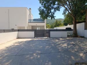 a white building with a tree and a fence at Holiday Home Iva - Three Bedroom Holiday Home in Šibenik