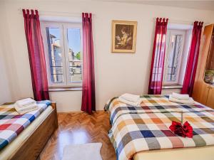 two beds in a room with red curtains at Sleek and Stylish Umag Apartments with Sea View - Comfort Two Bedroom Apartment with Terrace in Umag