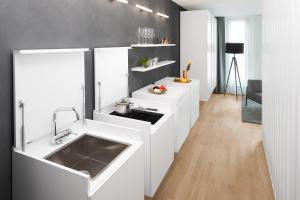a kitchen with white cabinets and a sink at AMANO HOME Apartments in Berlin