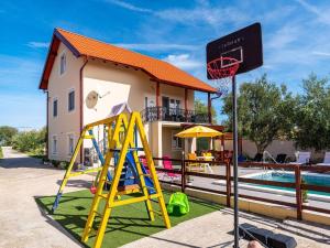 a playground in front of a house with a basketball hoop at Five Bedroom Villa in Zadar