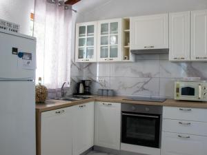 una cucina con mobili bianchi e un frigorifero bianco di Authentic Dalmatian Treasure Homes - House Wood a Orebić (Sabbioncello)