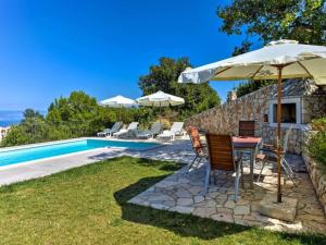 a table with an umbrella next to a swimming pool at Wonderful Brsec Apartments with Sea View and Shared Pool - Standard One Bedroom Apartment in Brseč
