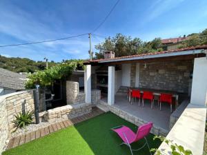 a patio with pink chairs and a table and grass at Family House Aldo - Family House with Four Bedrooms and Sea View in Rogač