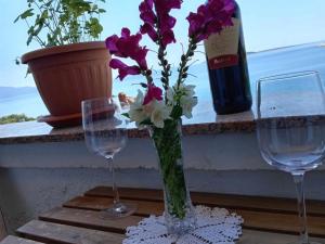 two wine glasses and a vase with purple and white flowers at Apartments Julia - Studio Apartment Julia 5 in Martinšćica +8 photos