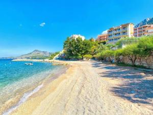 a sandy beach with buildings and the ocean at Apartmani Villa Borzic - One Bedroom Apartment with Terarce and Sea View in Omiš