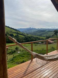 a hammock on a deck with a view of the mountains at La Maison De Bonneval in São Bento do Sapucaí +6 photos