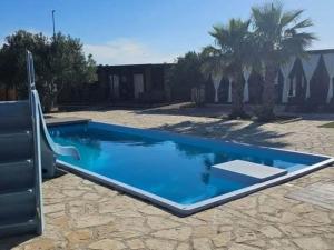 a blue swimming pool in a yard with palm trees at Gabrijela House - House in Pirovac