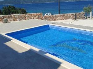 a blue swimming pool with the ocean in the background at Villa Tamaris - Two Bedroom Holiday Home with Terrace and Swimming pool in Mali Drvenik +12 photos