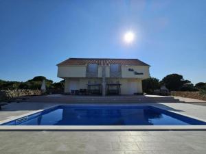 a house with a swimming pool in front of a house at Villa Tamaris - Two Bedroom Holiday Home with Terrace and Swimming pool in Mali Drvenik