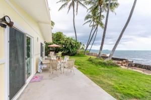 eine Terrasse mit Tisch und Stühlen und dem Meer in der Unterkunft Oceanfront Stay w/ AC, BBQ, Washer/Dryer & Kitchen in Ewa Beach