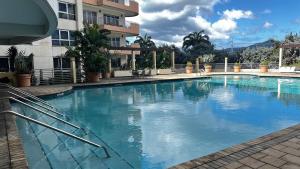 a large swimming pool in front of a building at 1-bedroom One Woodbrook Place Apartment! in Port-of-Spain +4 photos