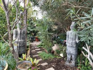 a garden with two statues in the middle of a path at Eden's Studio in Sellicks Beach