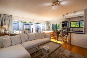 ein Wohnzimmer mit einer weißen Couch und einem Tisch in der Unterkunft Viletta Hauraki by Waiheke Pure in Waiheke Island
