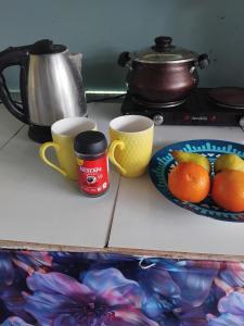 deux tasses et une assiette d'oranges sur un comptoir dans l'établissement CORAL Retreat, à Rewasau