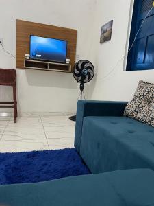a living room with a blue couch and a flat screen tv at Casa aconchegante em Barra de Caravelas in Caravellas