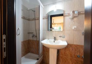 a bathroom with a sink and a shower and a mirror at Kipos Resort in Nea Peramos