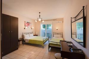 a bedroom with two beds and a mirror at Kipos Resort in Nea Peramos +37 photos