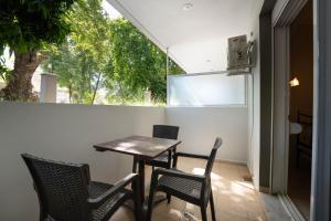 a table and chairs on a balcony with a window at Kipos Resort in Nea Peramos