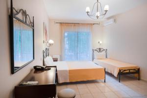 a bedroom with two beds and a desk and a window at Kipos Resort in Nea Peramos