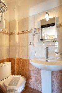 a bathroom with a sink and a toilet and a mirror at Kipos Resort in Nea Peramos