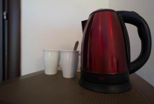a red tea kettle sitting on a table with two cups at Kipos Resort in Nea Peramos