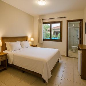 バヘイリーニャスにあるPousada Vila Lençóis Sport & Pousadaの大きなベッドとバスルームのある寝室