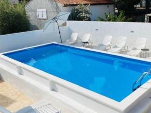una gran piscina azul con sillas y sombrilla en Villa Brazza - Studio Apartment, en Milna 11 fotos más