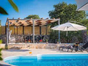 a swimming pool with an umbrella and an outdoor grill at Holiday Home Rider - Two Bedroom Holiday Home with Outdoor Pool in Vrpolje
