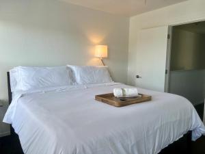 a white bed with a wooden tray on it at By Popular Demand - Richmond in Richmond