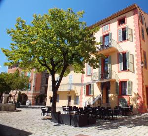 un albero di fronte a un edificio con tavoli e sedie di La Maison de la Tour a La Tour