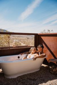 Un uomo e una donna seduti in una vasca da bagno di Sacred Sands - Lobo Luna a Joshua Tree