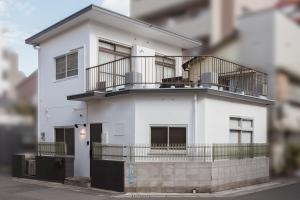 a white house with a balcony on a street at YokaYado Kagoshima Chuo - Retro Style Japanese Modern Entire House with Rooftop Balcony in Kagoshima