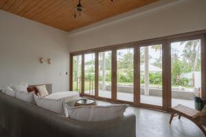 a living room with a large couch and windows at Naiya Villa in Piyadigama