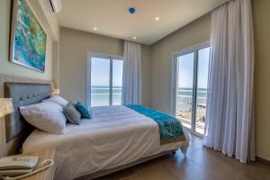 a bedroom with a bed with a view of the ocean at Zodiac Hotel Apartments in Larnaca