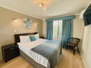 a bedroom with a bed and a chair and a window at Bay Village Dunsborough in Dunsborough