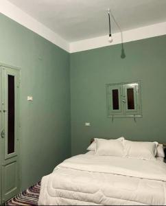 a bedroom with a large bed with green walls at Siwawi house in Siwa +21 photos