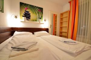 ein Bett mit weißen Laken und Handtüchern darauf in der Unterkunft AJO Apartments - Alte Donau Garden Flat - Self-Check-in in Wien