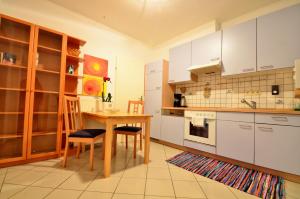 eine Küche mit weißen Schränken und einem Tisch und Stühlen in der Unterkunft AJO Apartments - Alte Donau Garden Flat - Self-Check-in in Wien
