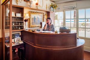 a woman standing behind a bar in a store at Hotel Tina in Diano Marina