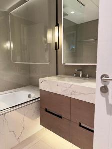 a bathroom with a tub and a sink and a mirror at Address Beach Resort Fujairah Apartment by Blue World - 5 in Fujairah