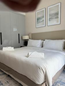 a bedroom with a large white bed with two pillows at Address Beach Resort Fujairah Apartment by Blue World - 5 in Fujairah