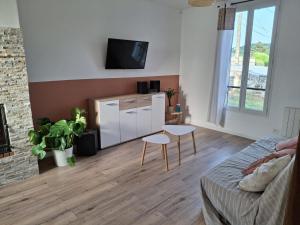 a living room with a couch and a tv on a wall at La petite broussaille in Autrêches