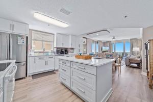 eine große Küche mit weißen Schränken und ein Wohnzimmer in der Unterkunft Beach Club B1701-New Rental- Gorgeous Corner unit in Gulf Shores