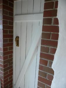 eine weiße Tür in einem Backsteingebäude neben einer Backsteinmauer in der Unterkunft Apartment am Lühedeich in Jork