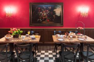 una sala da pranzo con due tavoli e un dipinto sul muro di Hotel im Hof a Monaco