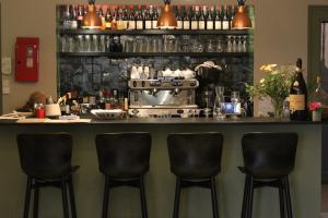 un bar avec trois tabourets de bar dans une pièce dans l'établissement Hôtel Courtille de Solutré, à Solutré-Pouilly
