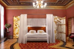 a bedroom with a bed with white curtains and a chandelier at Hotel Saturnia & International in Venice